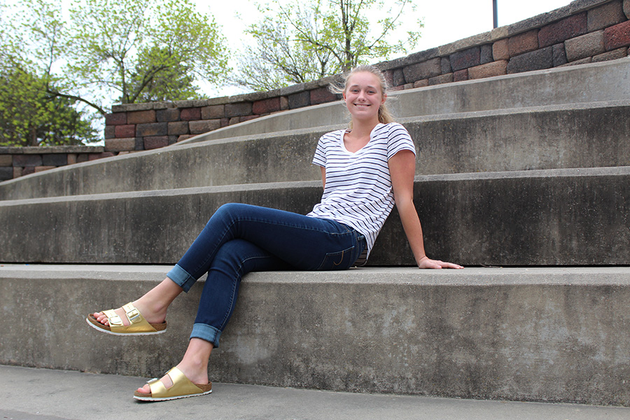 Madeleine Slattery ’19 lounges on the amphitheatre steps in the West High courtyard while wearing a striped top from Target, jeans from American Eagle and her favorite gold Birkenstocks.