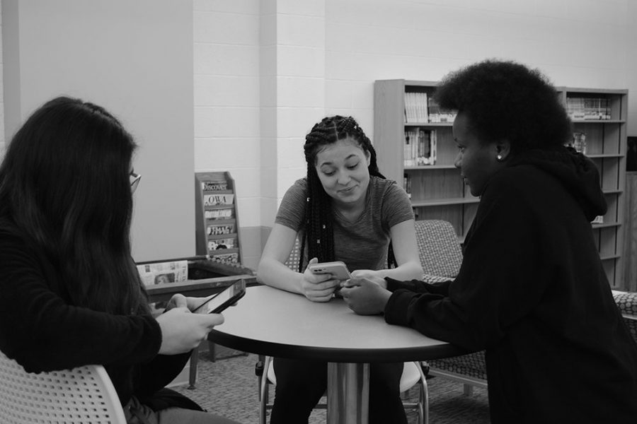 Pauline Kihura, Angie German, and Simone Willis, 20’ converse in the library while discussing good spots to take pictures for journalism.