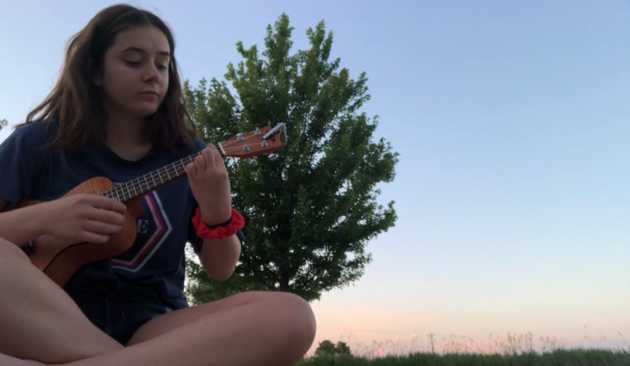 Tess DeGrazia 23 playing her ukulele outside.