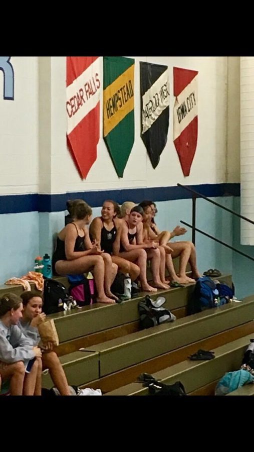 Jessica Nauman 23 and her swimming teammates are sitting on a bench during a swim meet.